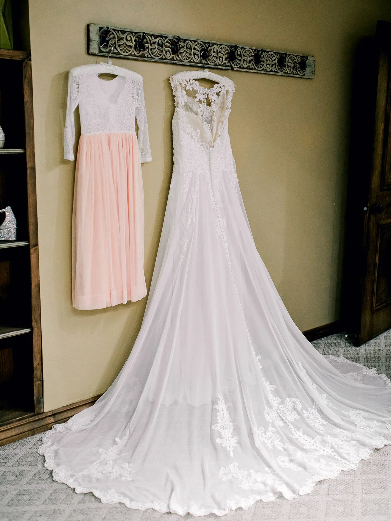 Jeff and Kasey The Palace Wedding - myheartcreative A white, lace wedding gown hangs from a rustic coat rack. The pink and white lace dress belonging to the bride's daughter hangs next to it.