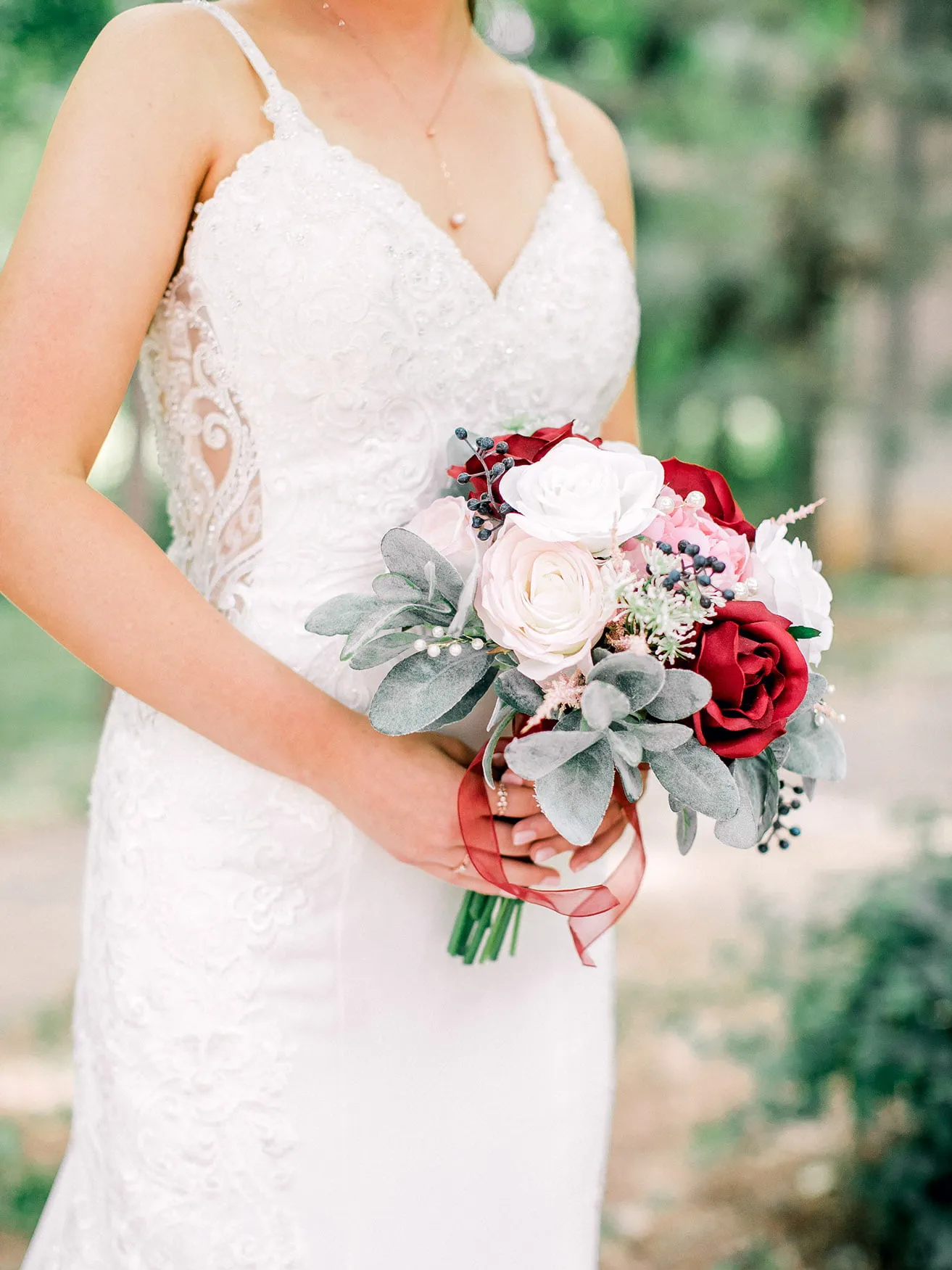 Derek and Shelby Thunderbird Chapel Wedding - myheartcreative The bride holds her red, white, and pink bouquet while wearing a sleeveless, lace wedding gown.