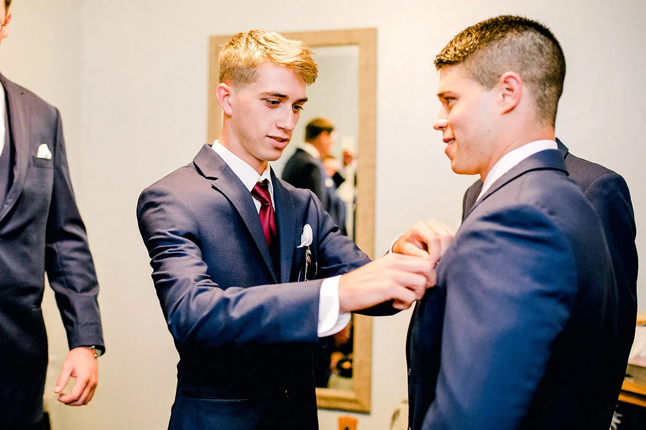 Derek and Shelby Thunderbird Chapel Wedding - myheartcreative A groomsmen adjusts Derek's boutonniere as they get ready in the venue's grooms suite.