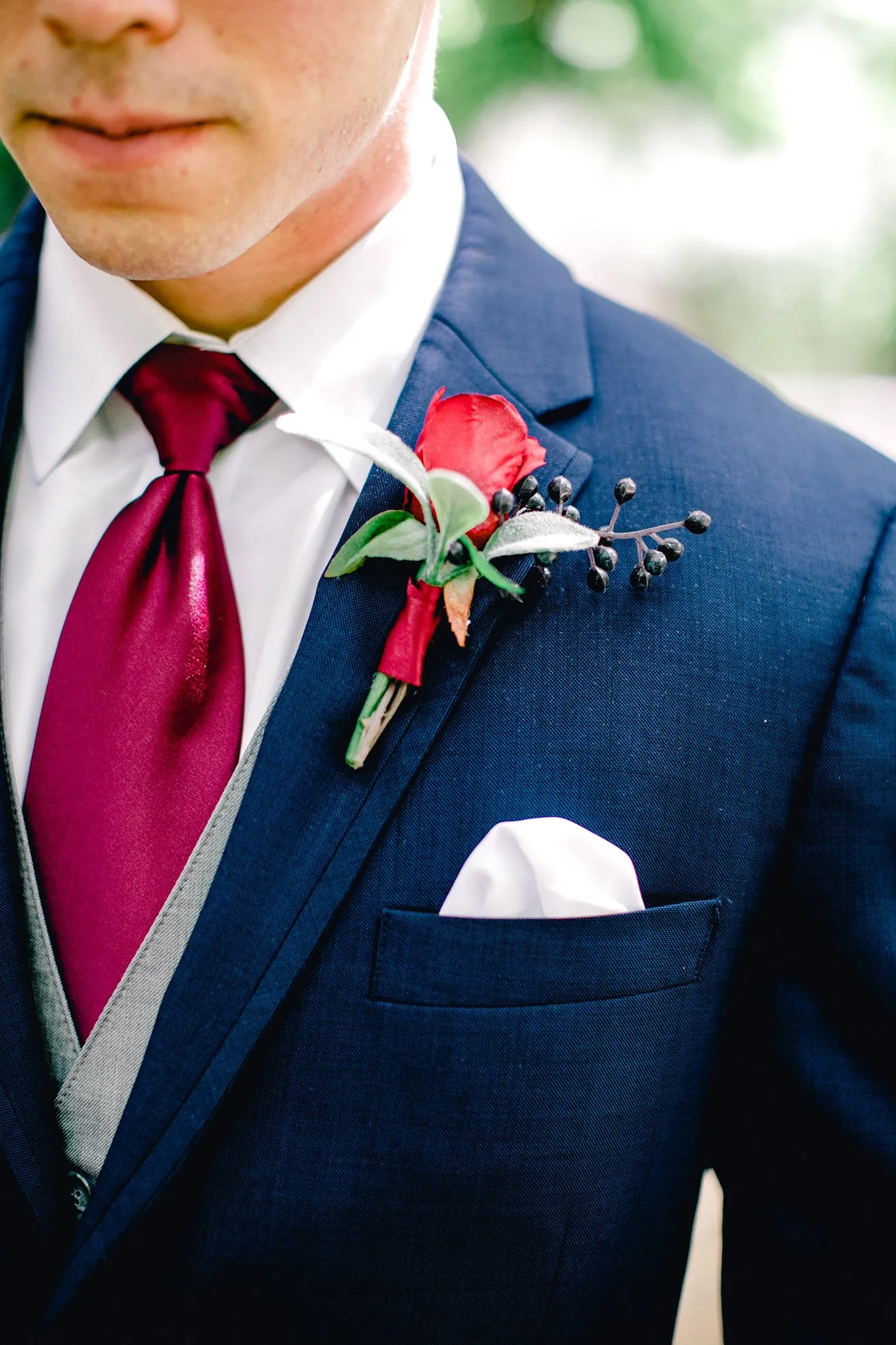 Derek and Shelby Thunderbird Chapel Wedding - myheartcreative An up-close shot of the groom's boutonniere and pocket handkerchief attached to his navy blue suit and maroon tie.