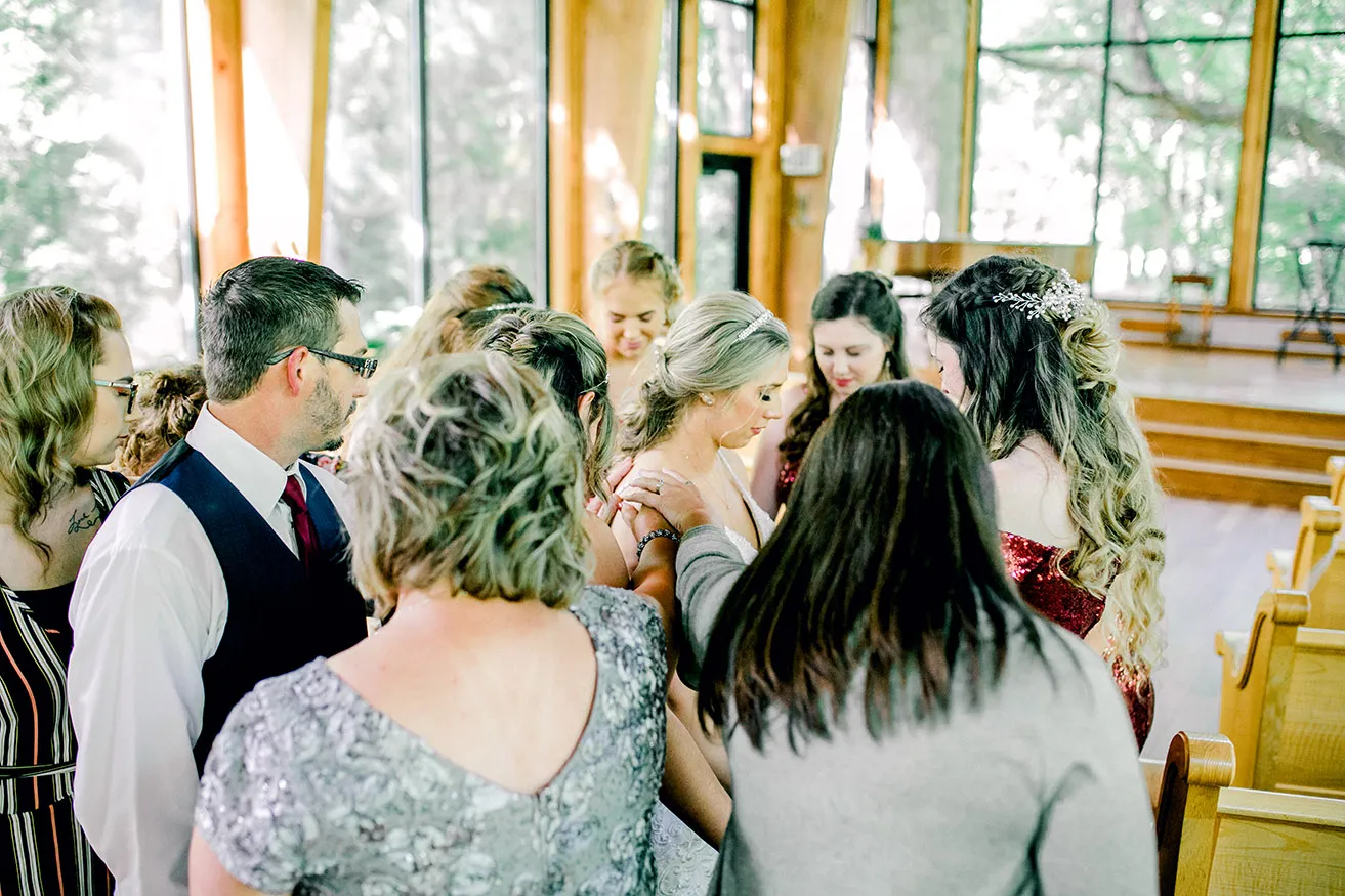 Derek and Shelby Thunderbird Chapel Wedding - myheartcreative The bride's family and bridesmaids surround Shelby and hold their hands on her shoulders as they pray.