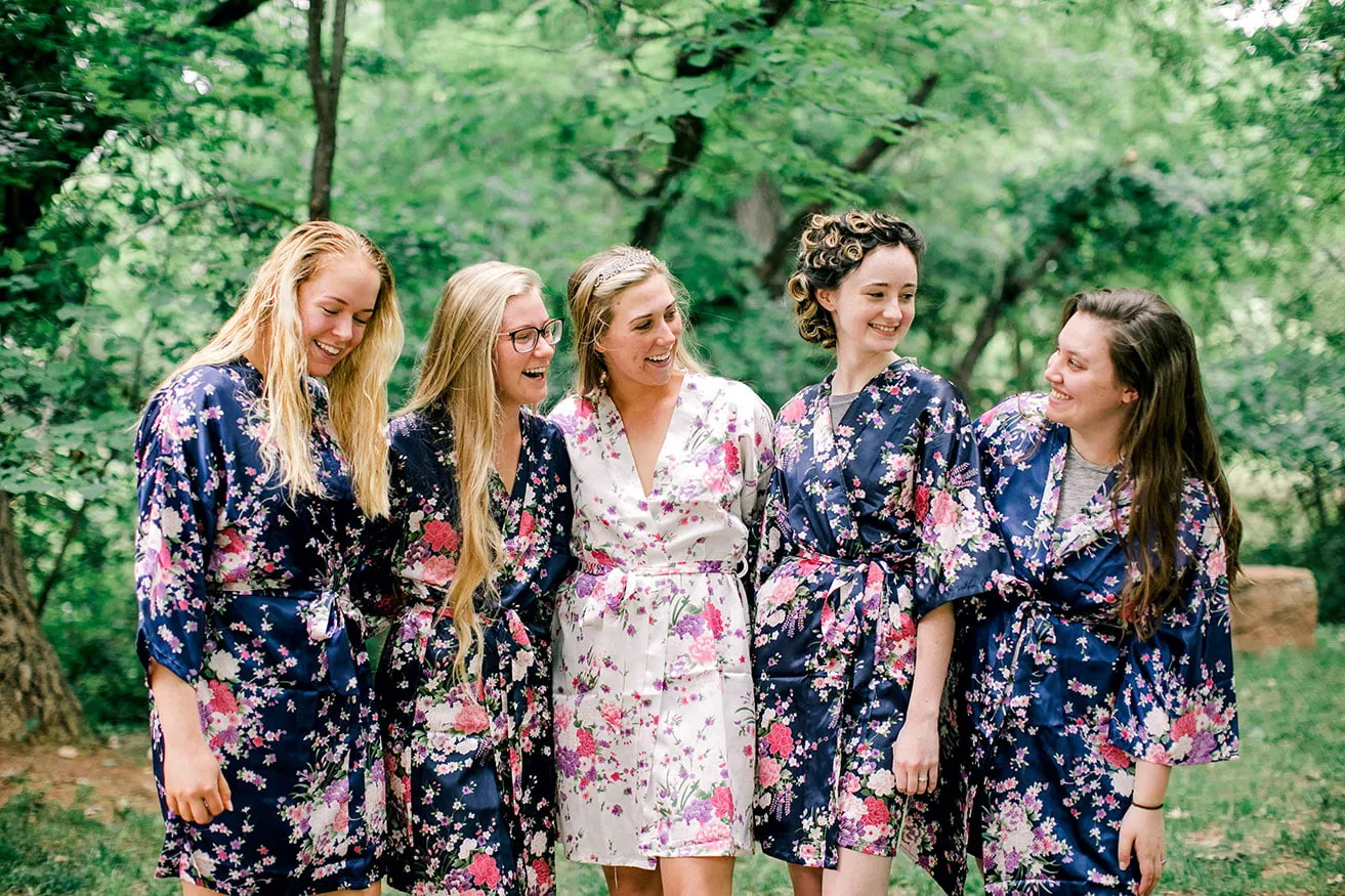 Derek and Shelby Thunderbird Chapel Wedding - myheartcreative Shelby wears a white floral robe as she smiles with four bridesmaids, all wearing navy blue floral robes.