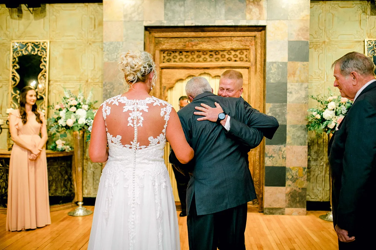 Jeff and Kasey The Palace Wedding - myheartcreative The groom hugs the bride's father as they reach the end of the aisle at the ceremony.
