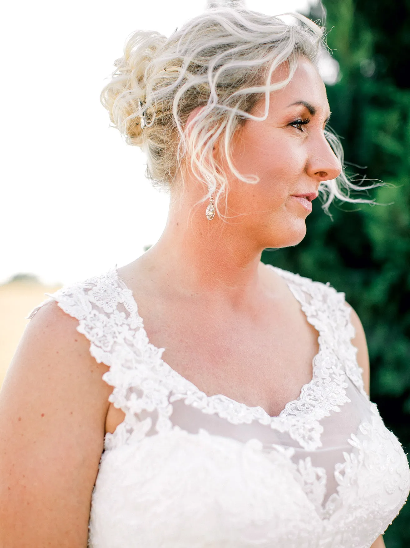 Jeff and Kasey The Palace Wedding - myheartcreative A detail shot of the bride. She is wearing a white lace gown diamond earrings with her hair in a loose updo.
