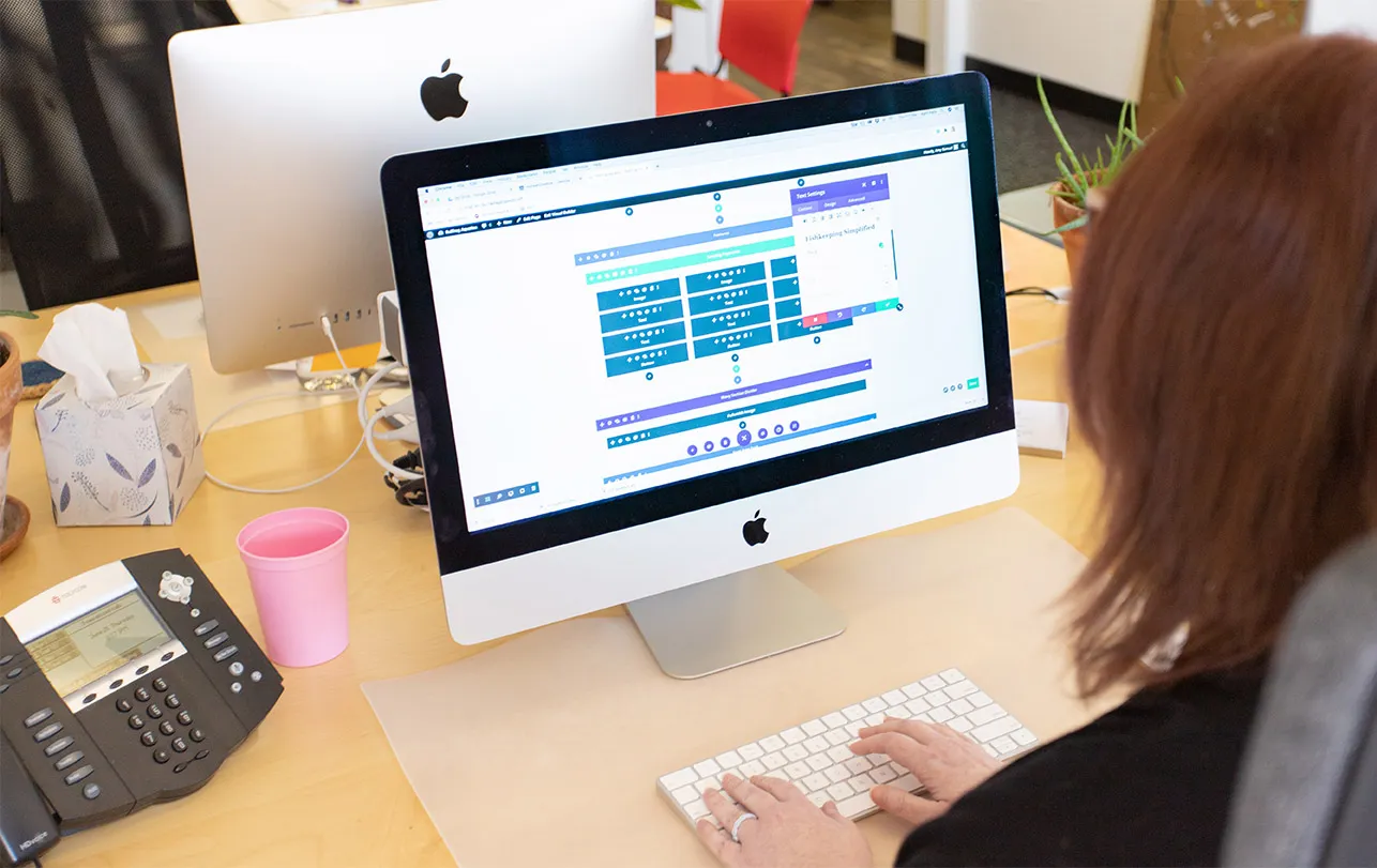 Why Is SEO Friendly Website Design Important? - myheartcreative April sits at her desk and edits a client's OKC web design using the WordPress Divi builder.