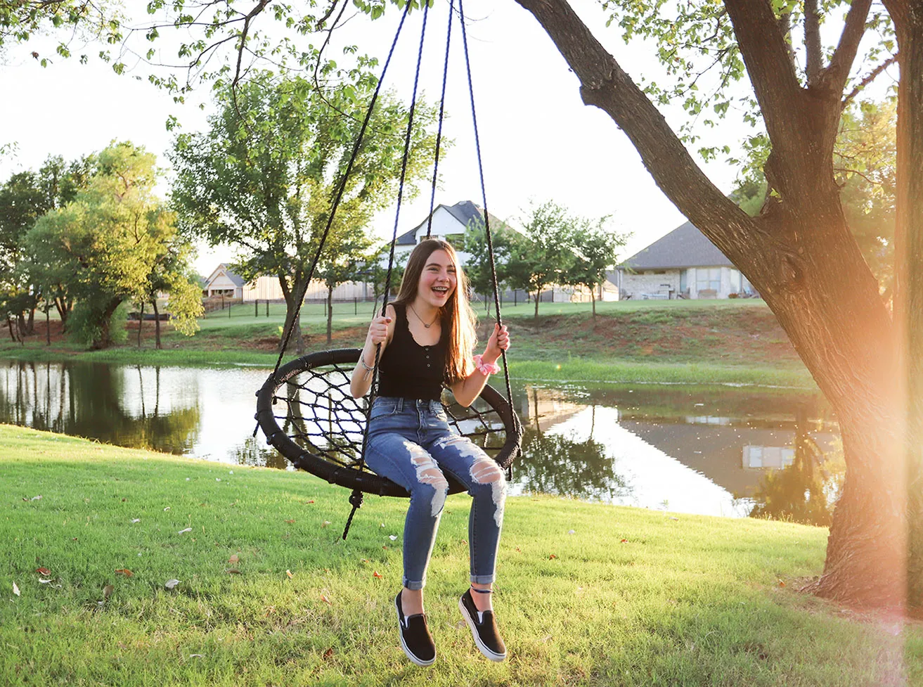 A teenage girl sits in a tree swing during a Porchtrait. 