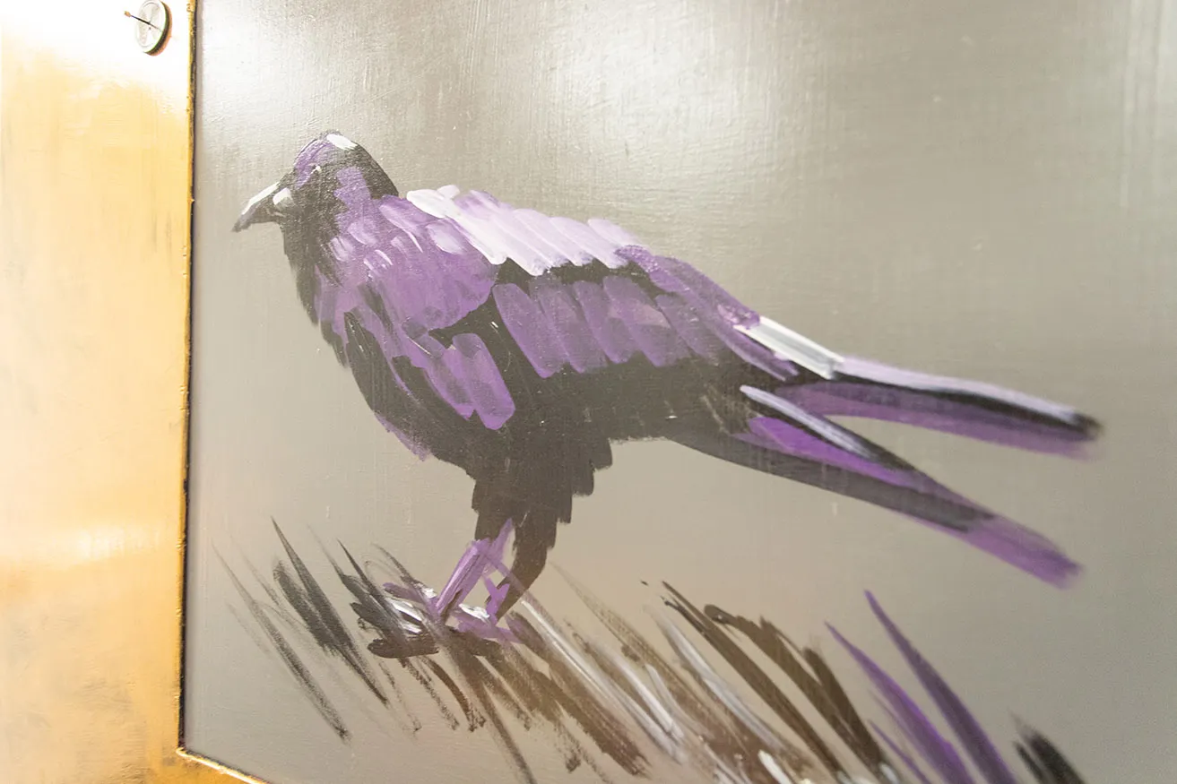 An up-close shot of a painting of a black crow by Dr. Bob Palmer. 