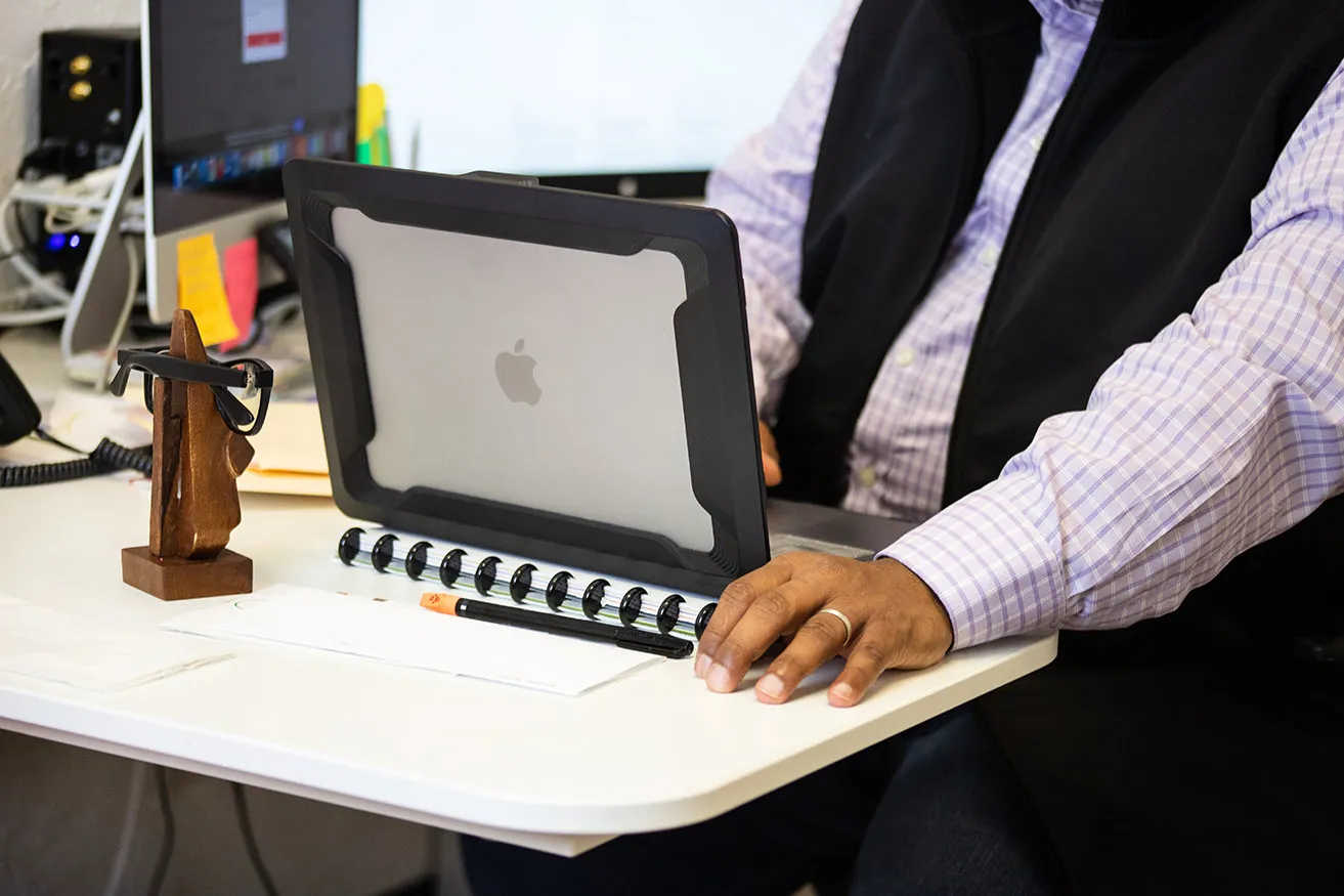 Sam reviews client metrics in his office on his Macbook laptop. 