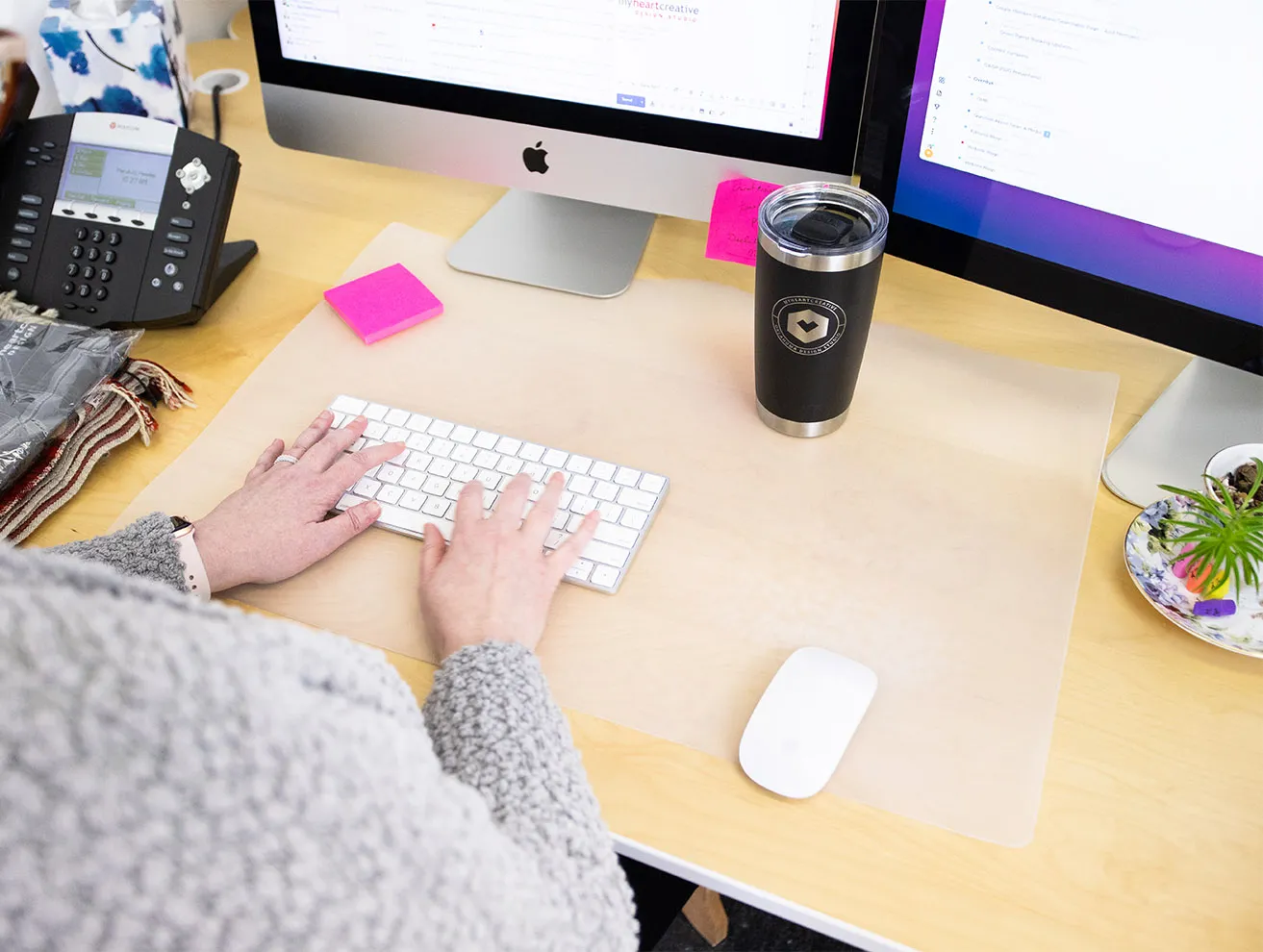 The Pros and Cons of Separating a Blog from a Website - myheartcreative April types on her keyboard at her desk while she drinks from a coffee mug with the myheartcreative logo etched on the front.