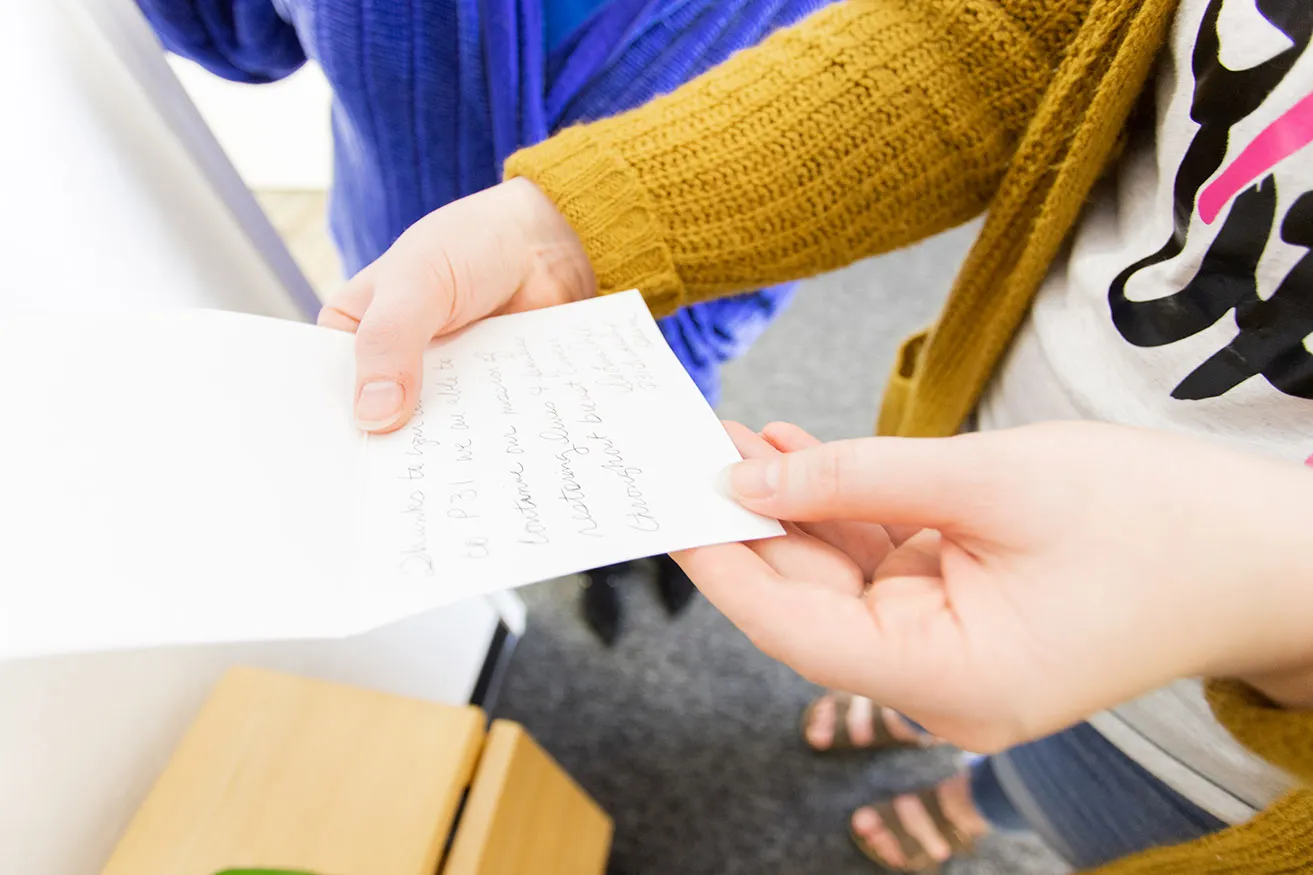 A myheartcreative employee holding a handwritten card to be sent to a client. 