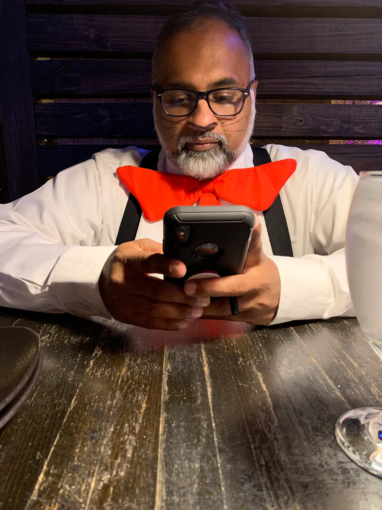 Sam is messaging clients while at a restaurant dressed as Cat in the Hat. 