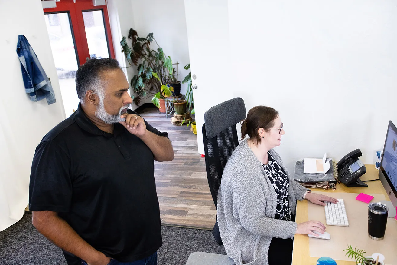 How Many People Does It Take to SEO? - myheartcreative Sam talking with April while she works on the content on a client's OKC website at her desk.