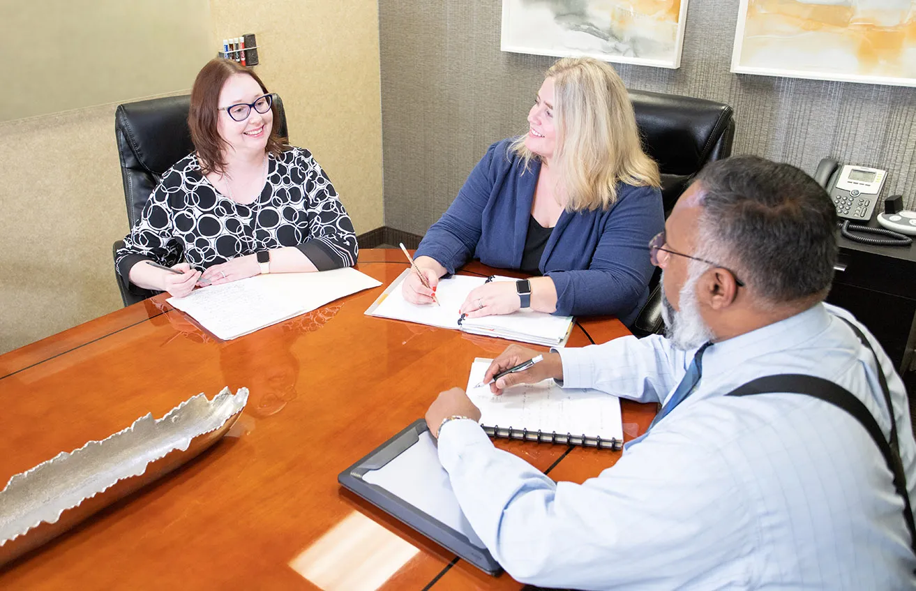 April, Sam, and Amy meeting together in an office to discuss a website design in Dallas. 