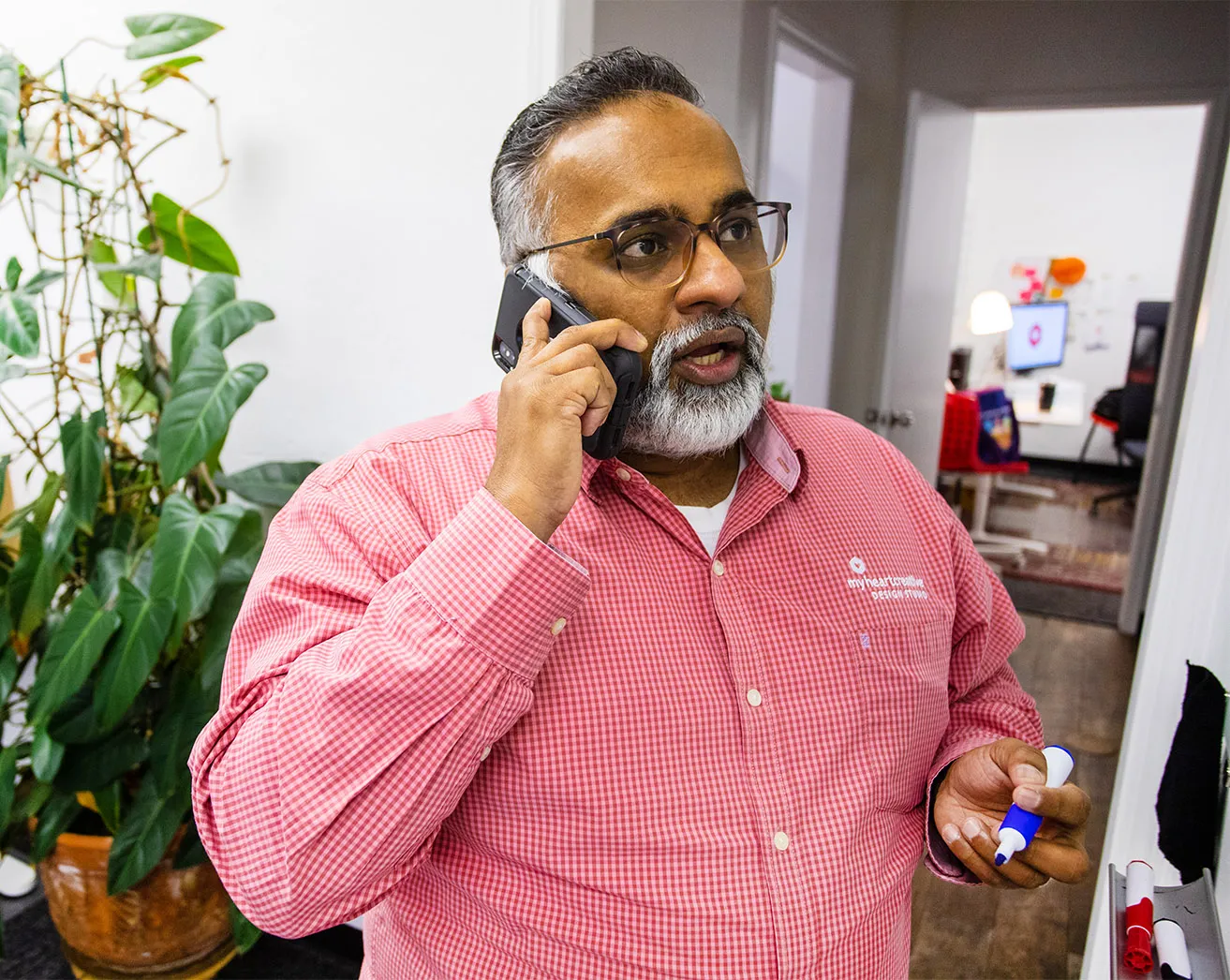 Sam, Operations Director at myheartcreative, talking on his cell phone with a digital marketing OKC client while writing goals on the studio whiteboard. 
