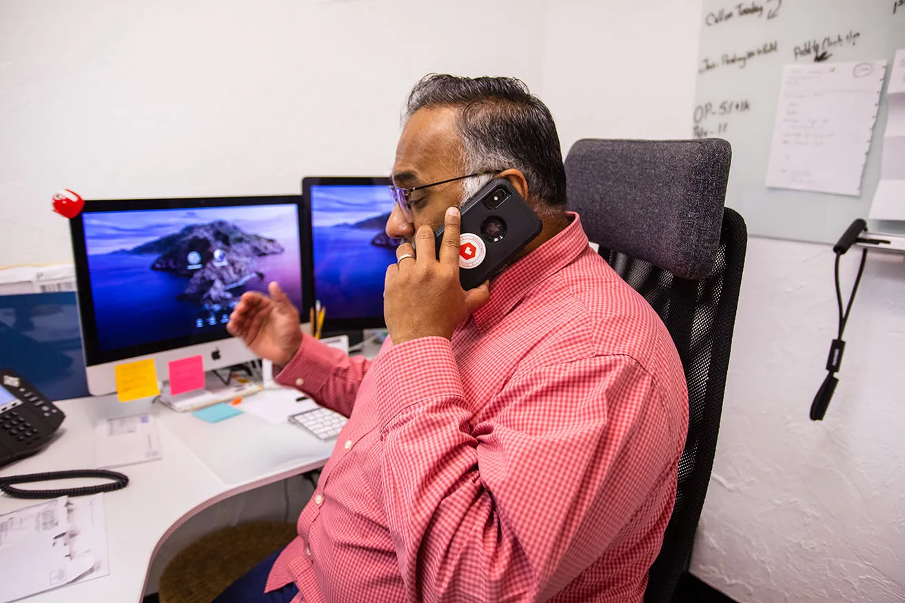Top 6 Benefits of Digital Marketing Dallas - myheartcreative Sam, Operations Director at myheartcreative, talking on his cell phone at his desk with an SEO marketing Dallas client.