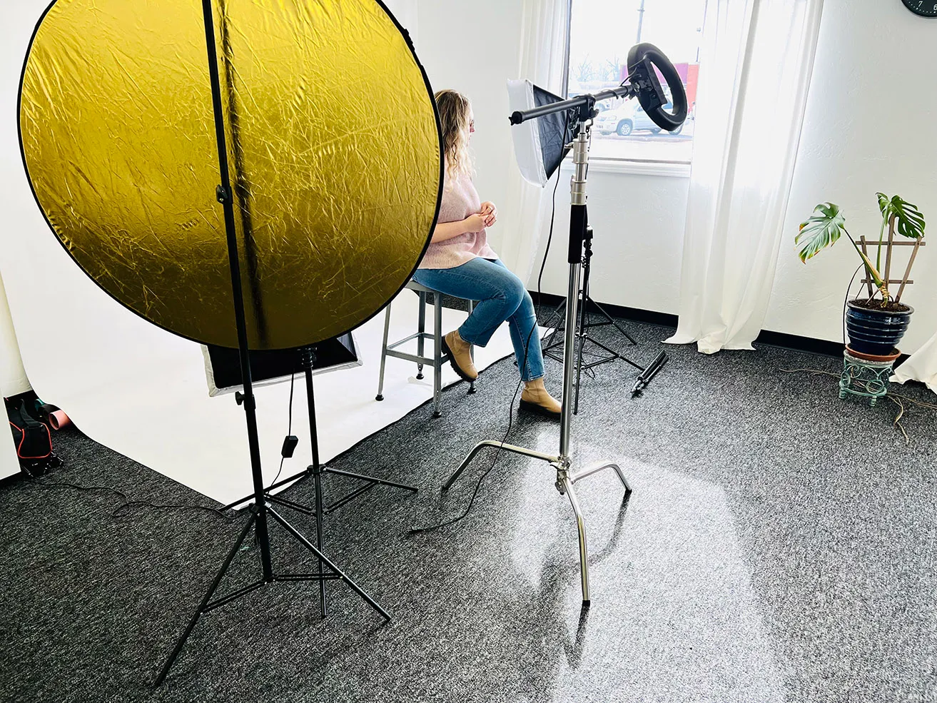 What is the Importance of Video Production OKC in Today’s Society? - myheartcreative A woman sits on a stool infront of a white photo backdrop at an Oklahoma Design studio.