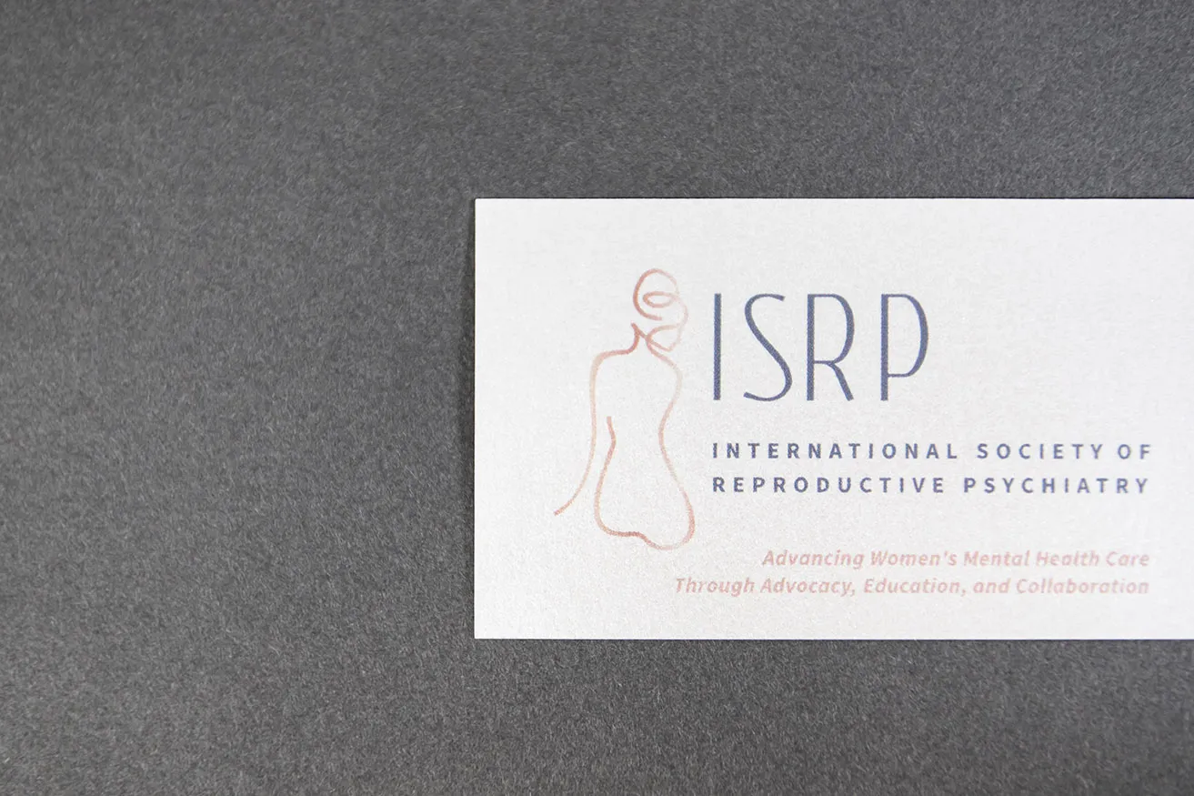 A business card designed for International Society of Reproductive Psychiatry with a light pink and grey logo and font.  "Advancing women's mental health care through advocacy, education, and collaboration."