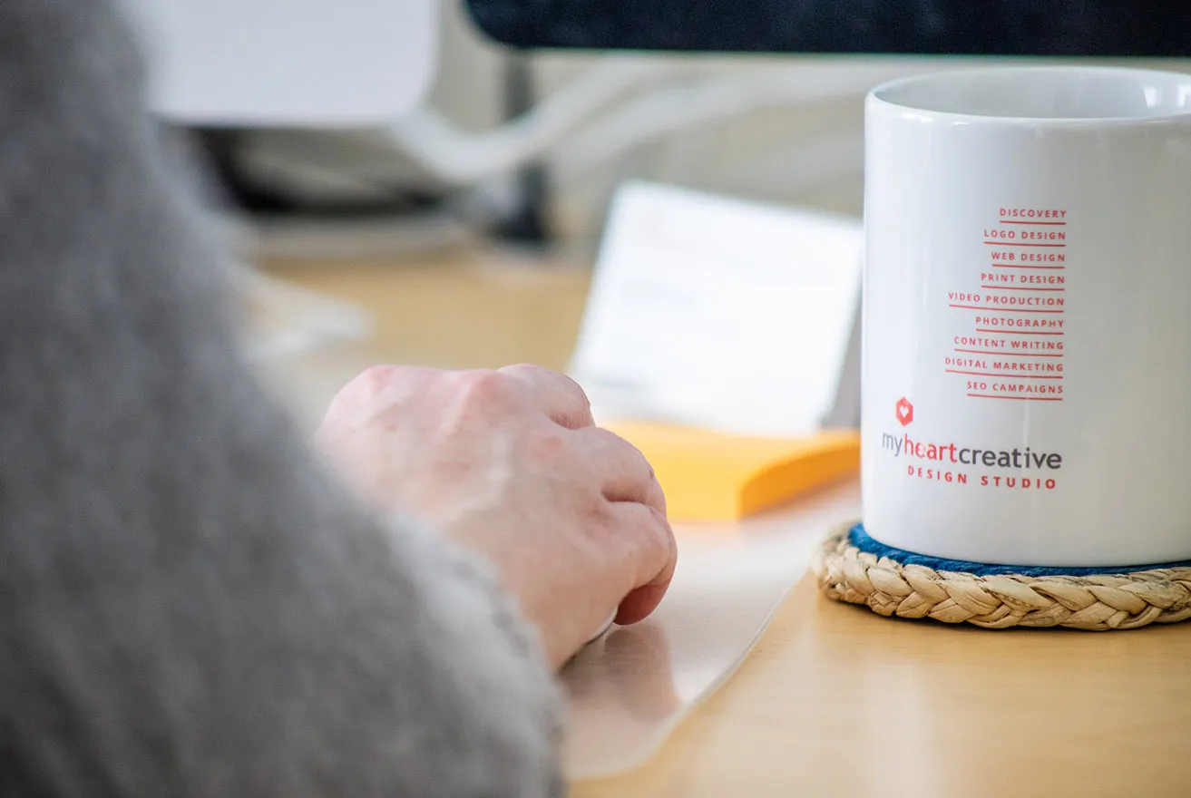 A writer making content edits on a client's web OKC design with a cup full of coffee next to her hand. 
