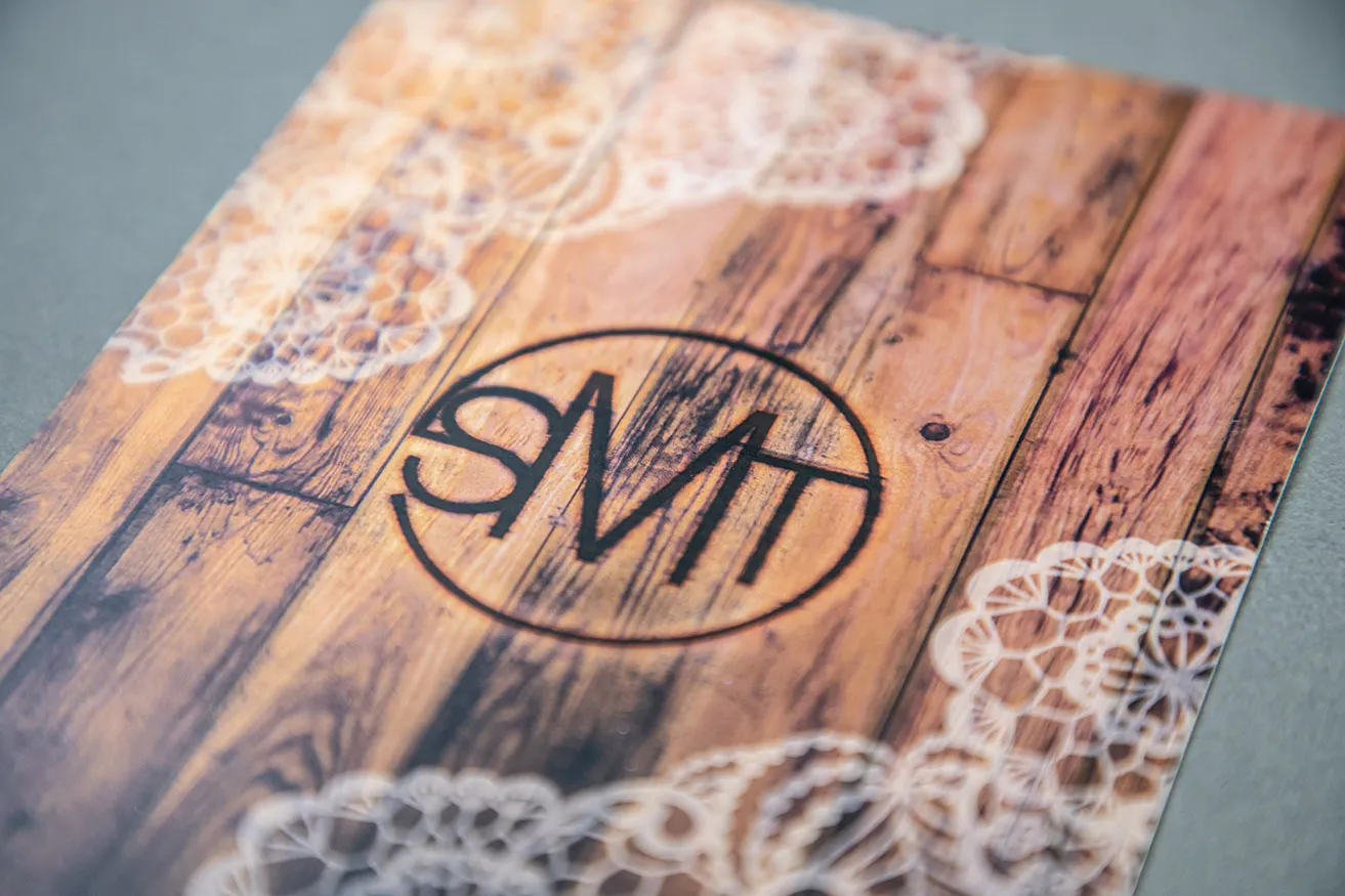 A Guide to the Monogram Design Process - myheartcreative A monogrammed wedding invitation with the initials S.M.T. on a rustic wood background.