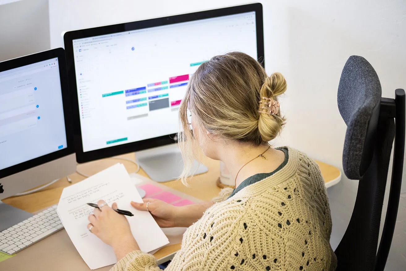 Website Design Dallas: How to Create Flow in a Blog - myheartcreative A content writer at the myheartcreative studio writes content on a piece of paper for a Dallas web design.