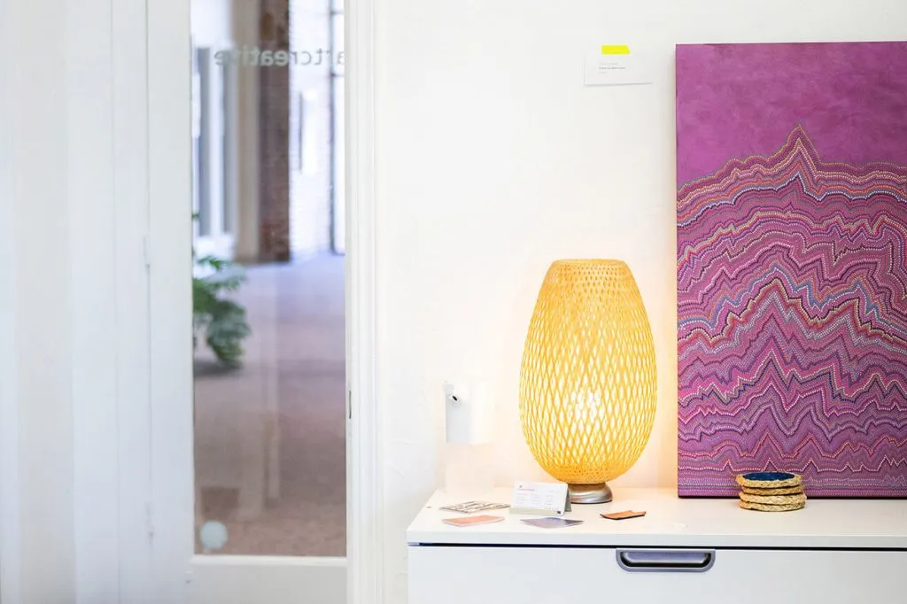 A purple abstract piece created by Oklahoma Artist Sara Cowan sits on a table next to a lamp in the conference room. 