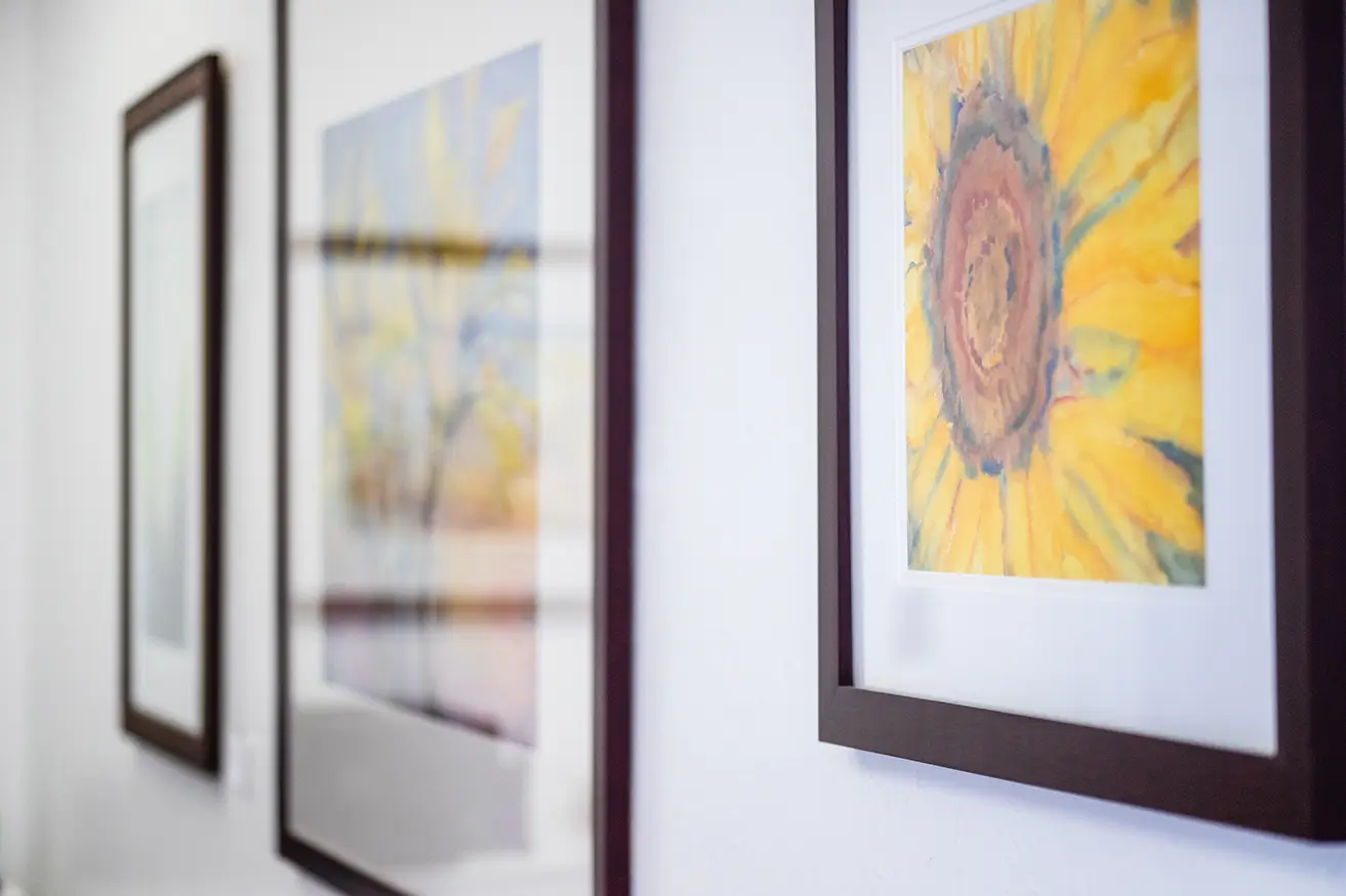 A watercolor painting of a sunflower hangs in the myheartcreative conference room, as two other pieces by Deborah Burian hang next to it. 