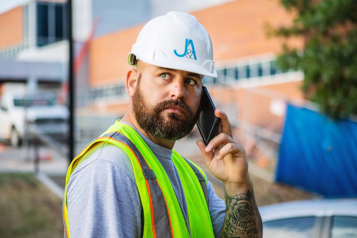 A JAUE employee talking to a client on his cell phone at a jobsite.