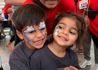 Three kids smile together at a charity race.