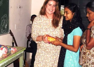 Amy hands a teenage girl a scarf in India.