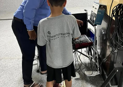 A young boy wearing a myheartcreative t-shirt learns about technology from a Make-A-Wish India employee.