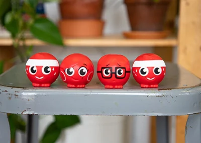 Four red noses with faces rest on a gray stool.