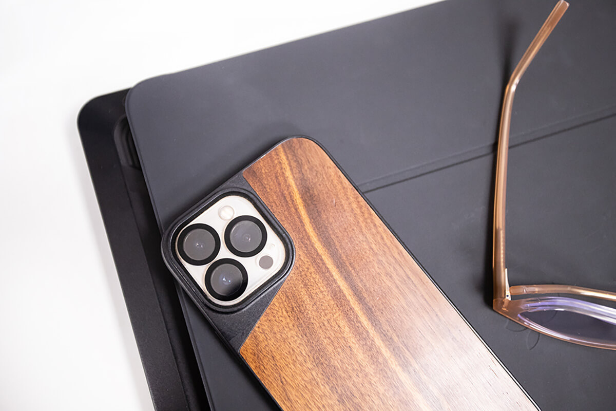 A smart phone with a brown case resting on a tablet. 