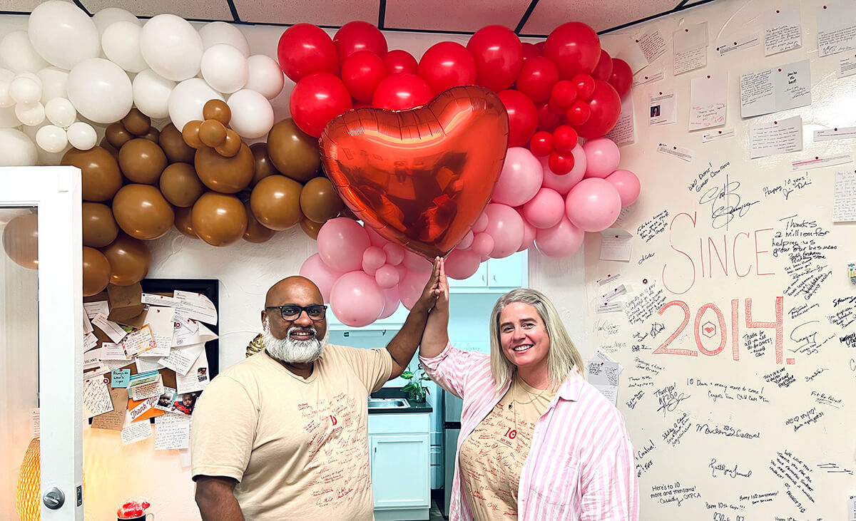 Sam and Amy high five under balloons at myheartcreative's 10th anniversary party. 