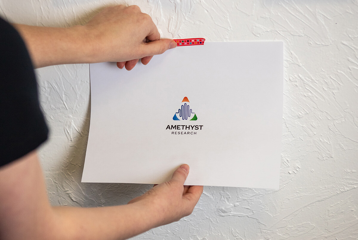 The studio assistant hanging up a print with Amethyst's completed logo. 