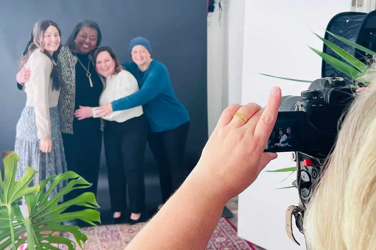 Women hugging behind a camera at a photoshoot