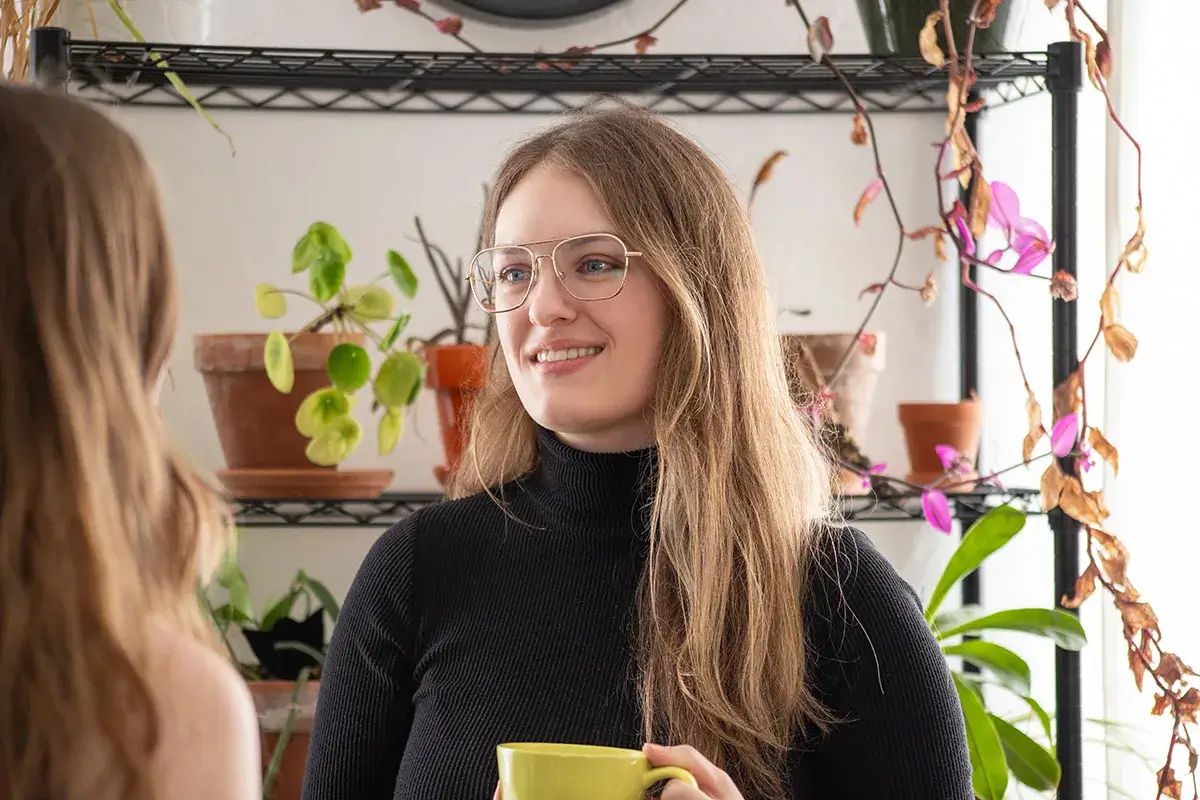 A project coordinator talking while holding a coffee cup